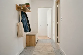 Entrée étroite bien rangée avec porte-manteau mural, étagère flottante et meuble à chaussures compact dans un appartement