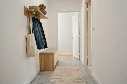 Entrée étroite bien rangée avec porte-manteau mural, étagère flottante et meuble à chaussures compact dans un appartement