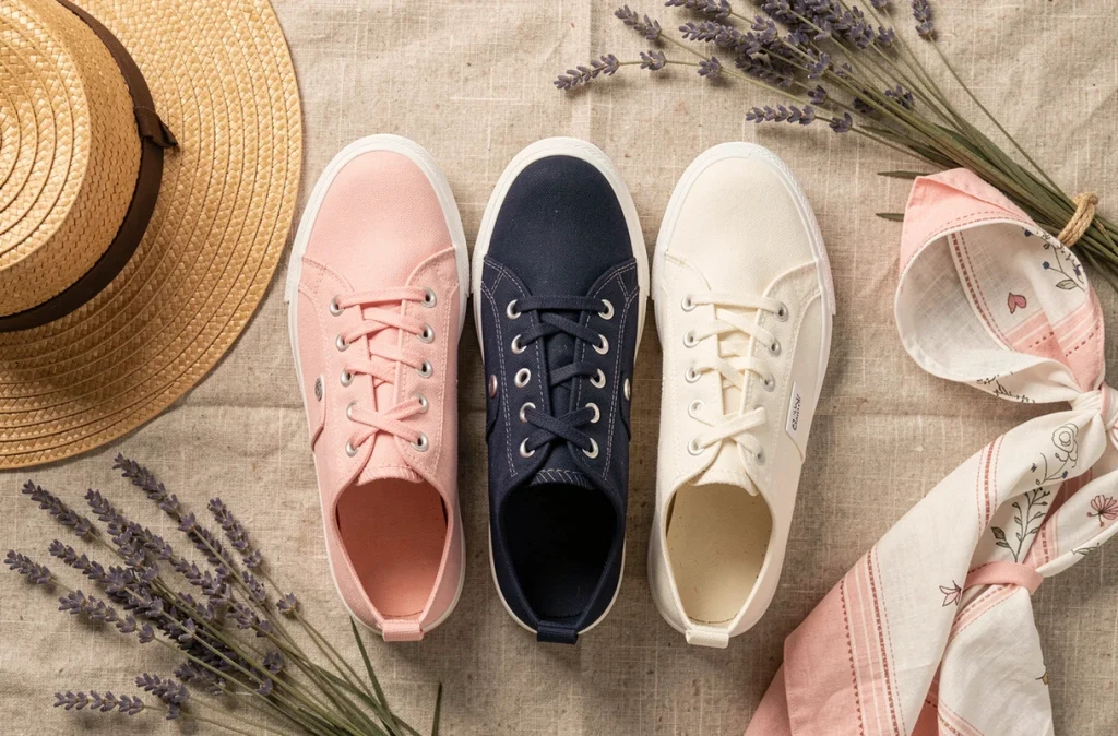 Flat lay de trois paires de chaussures en toile colorées avec accessoires de printemps sur fond de lin naturel